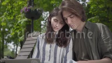 <strong>男生</strong>和女生穿着便服坐在长凳上，女生拿着笔记本电脑，<strong>男生</strong>手里拿着日记